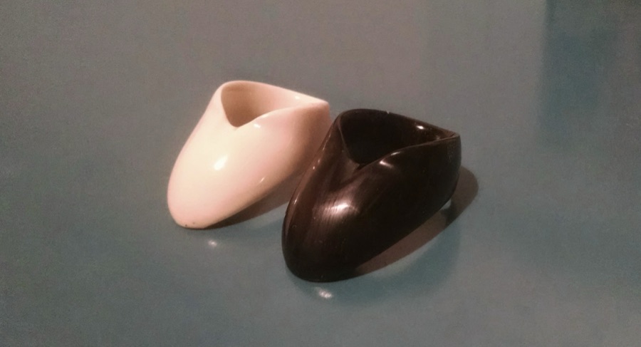 Two Vermil Victory thumb rings side by side, one ivory-white resin and one black.